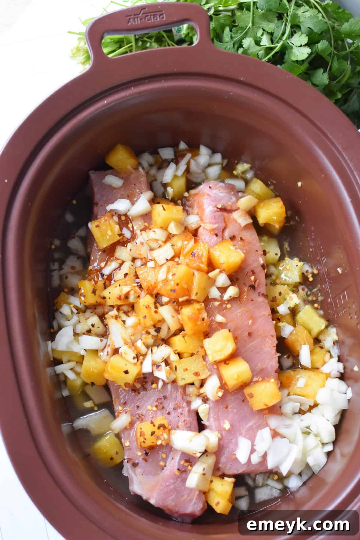 Slow Cooker Pineapple Pork Loin simmering in a crockpot with the sauce.