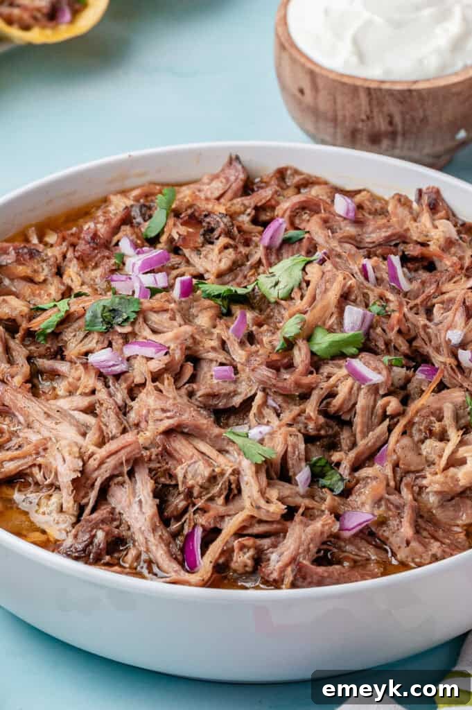 Melt-in-Your-Mouth Slow Cooker Pulled Pork Tacos 18 A large bowl filled with delicious Slow Cooker Pulled Pork Tacos, garnished with fresh cilantro and lime wedges, ready to be served.