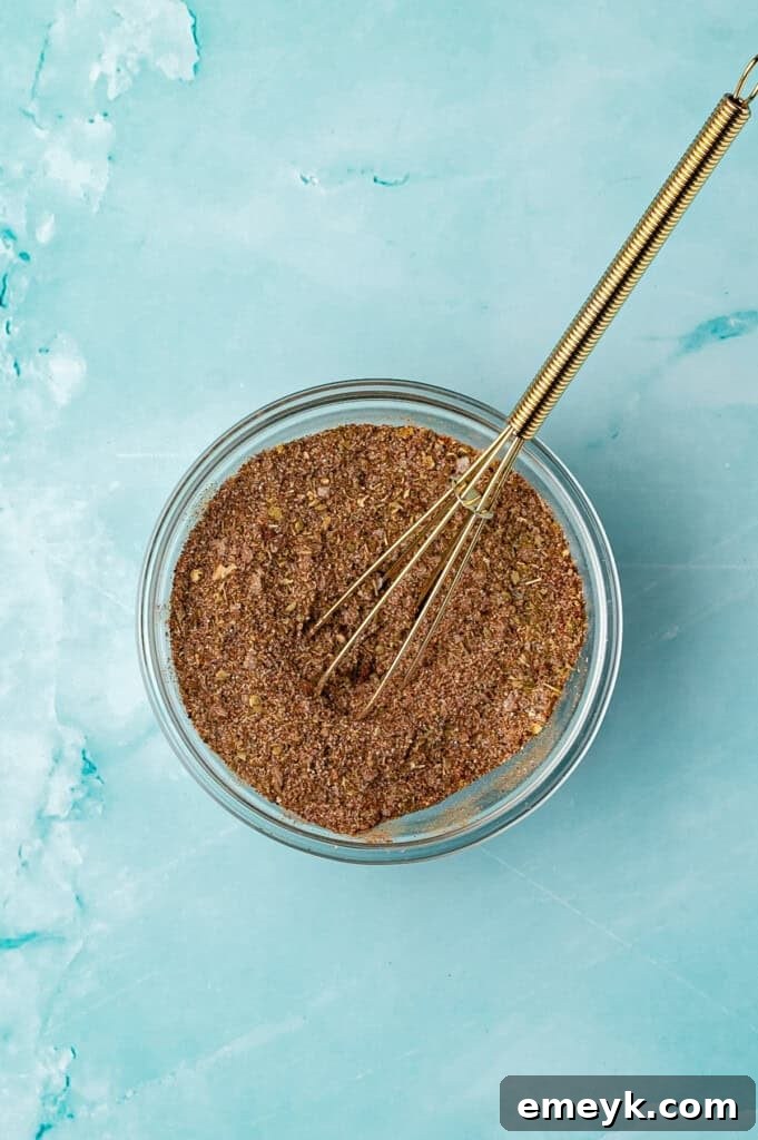 A small bowl containing the pre-mixed spice rub for the pulled pork, showing the vibrant colors of chili powder, cumin, and other spices.