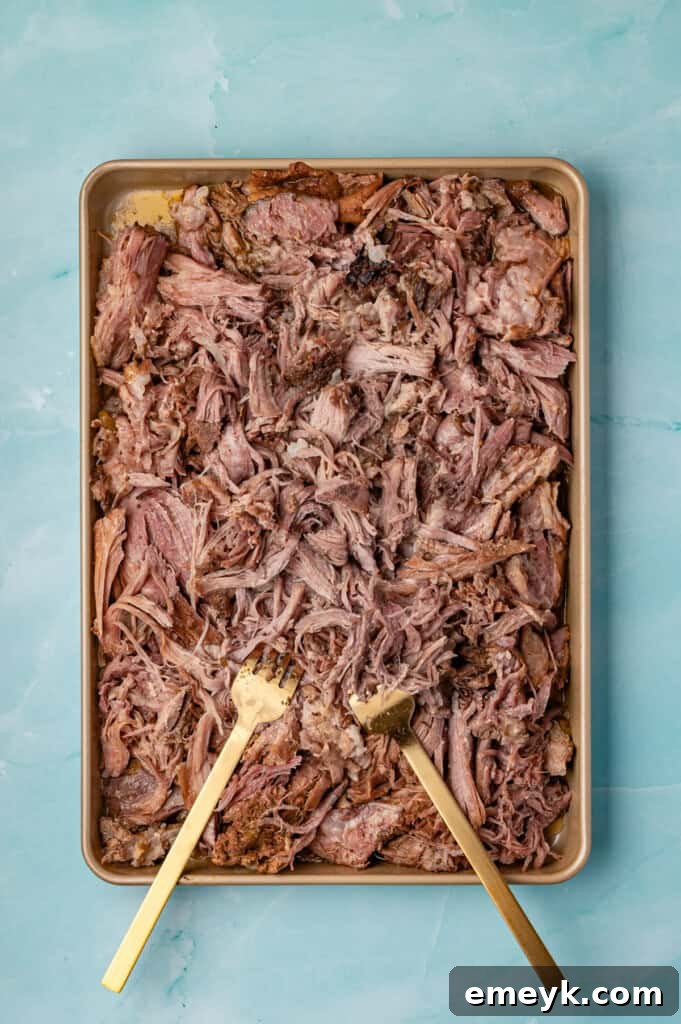 Shredded Slow Cooker Pulled Pork spread on a baking sheet, with some crispy edges, ready to be served or crisped further.