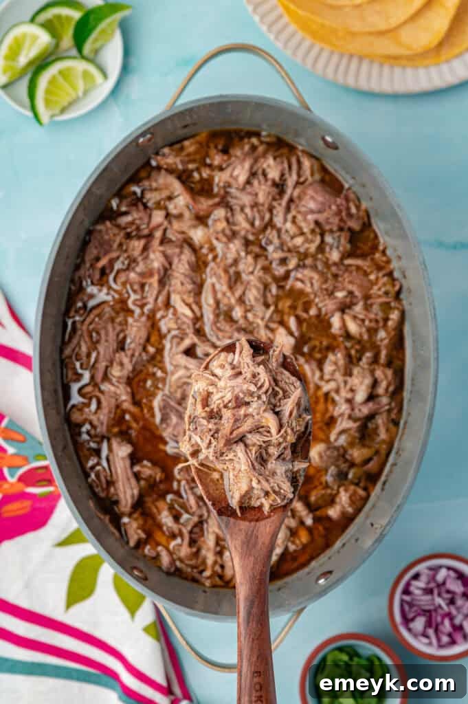 The tender pulled pork simmering in its flavorful juices inside the slow cooker, just before shredding.