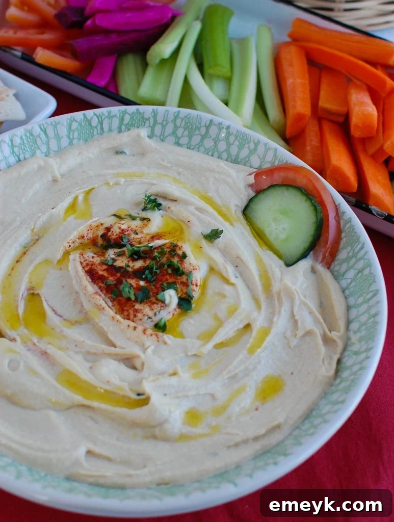 Freshly made Lebanese Hummus Recipe garnished with parsley and olive oil, served in a bowl with a side of pita bread, ready for dipping.