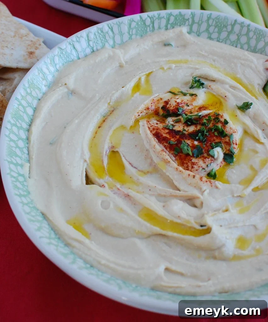Platter of fresh vegetables like carrots, cucumbers, and bell peppers arranged around a bowl of Lebanese Hummus, ready for a healthy snack.