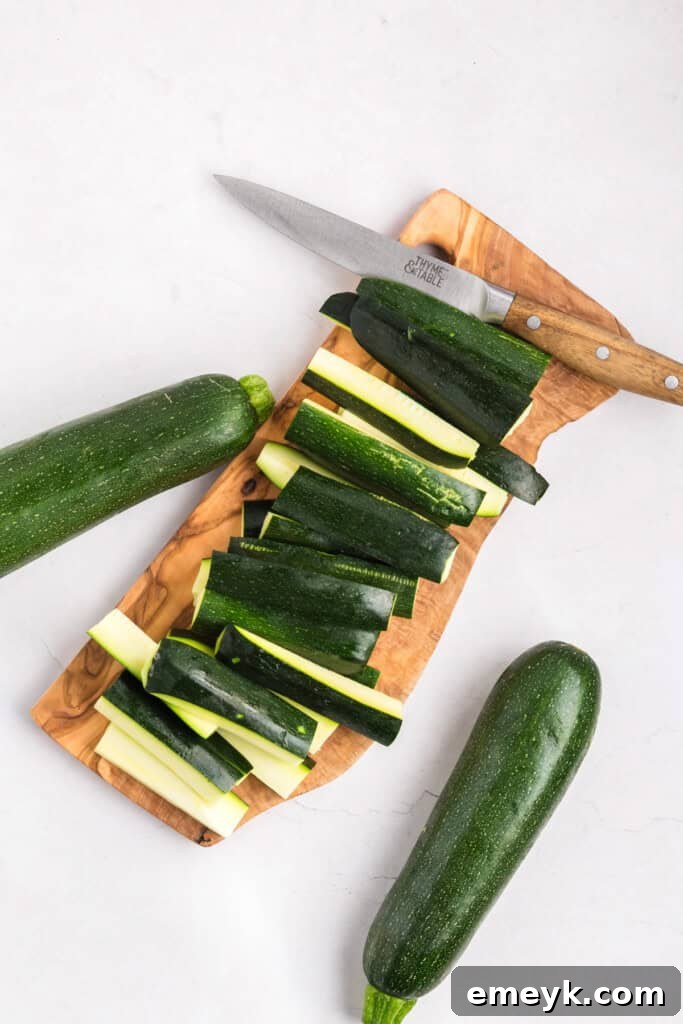 Crispy Air Fryer Zucchini Fries 11 Zucchini being cut into uniform sticks on a cutting board.