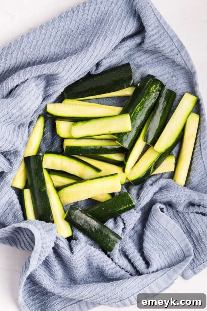 Crispy Air Fryer Zucchini Fries 12 Salted zucchini sticks resting in a colander to drain excess moisture.