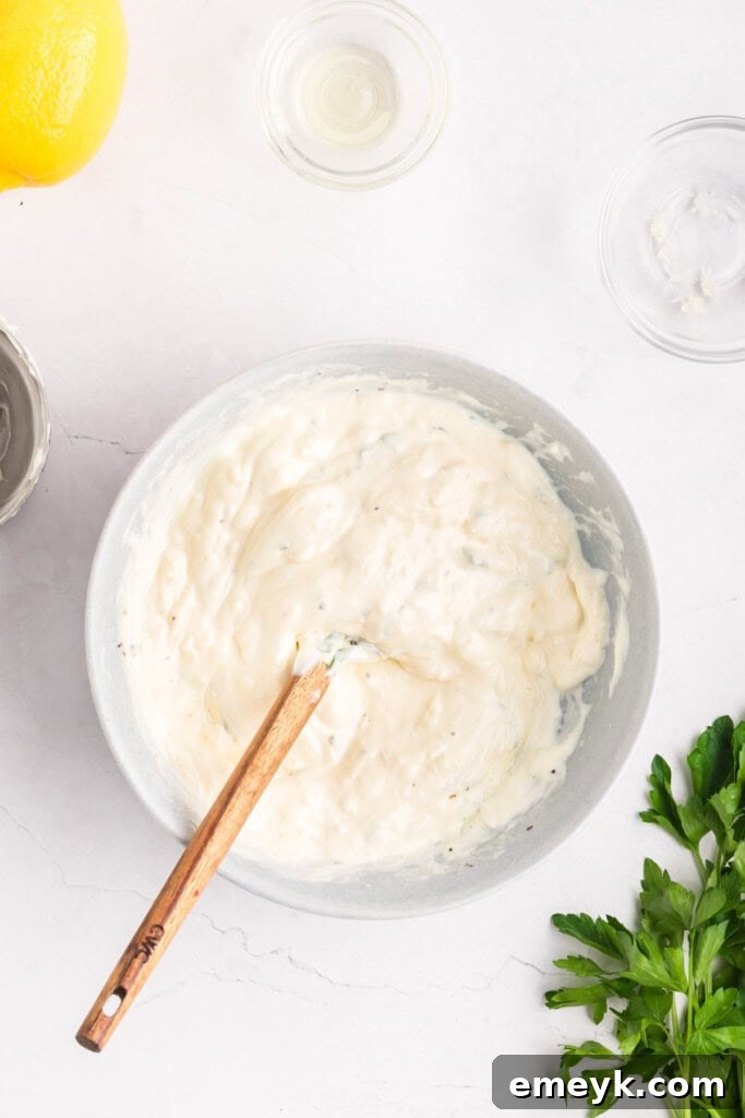 Crispy Air Fryer Zucchini Fries 10 Garlic Lemon Aioli being stirred with a spoon in a bowl.
