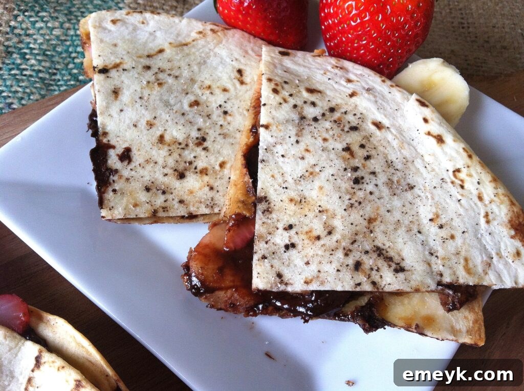 Delicious Dessert Quesadilla on a white plate, showcasing melted chocolate, sliced bananas, and strawberries.