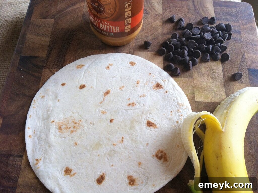A tortilla with a smooth layer of peanut butter spread on it, ready for the next delicious toppings.