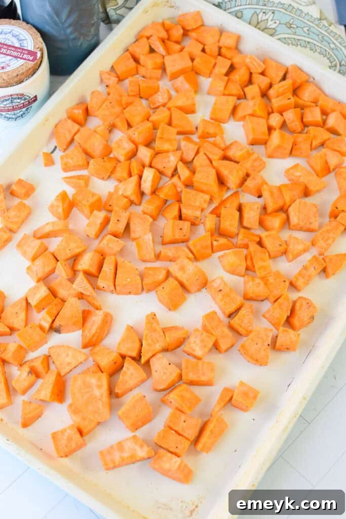 Roasted sweet potatoes spread evenly on a baking sheet, golden and tender, fresh out of the oven.