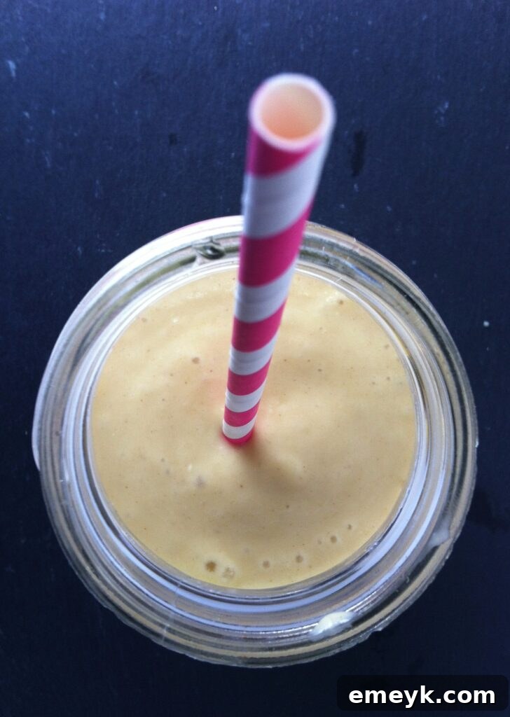 Close-up of a creamy Mango Banana Oatmeal Breakfast Smoothie in a glass, highlighting its smooth texture