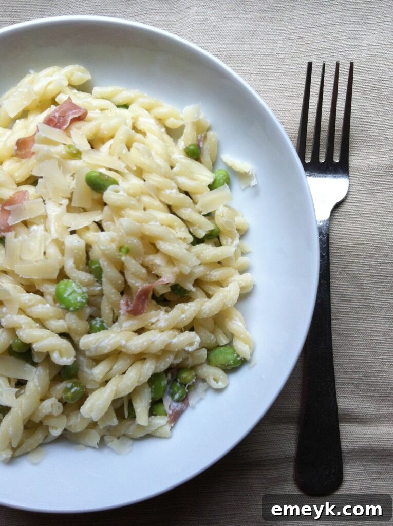 Fresh pasta dish with vibrant green peas and favas, garnished with herbs.