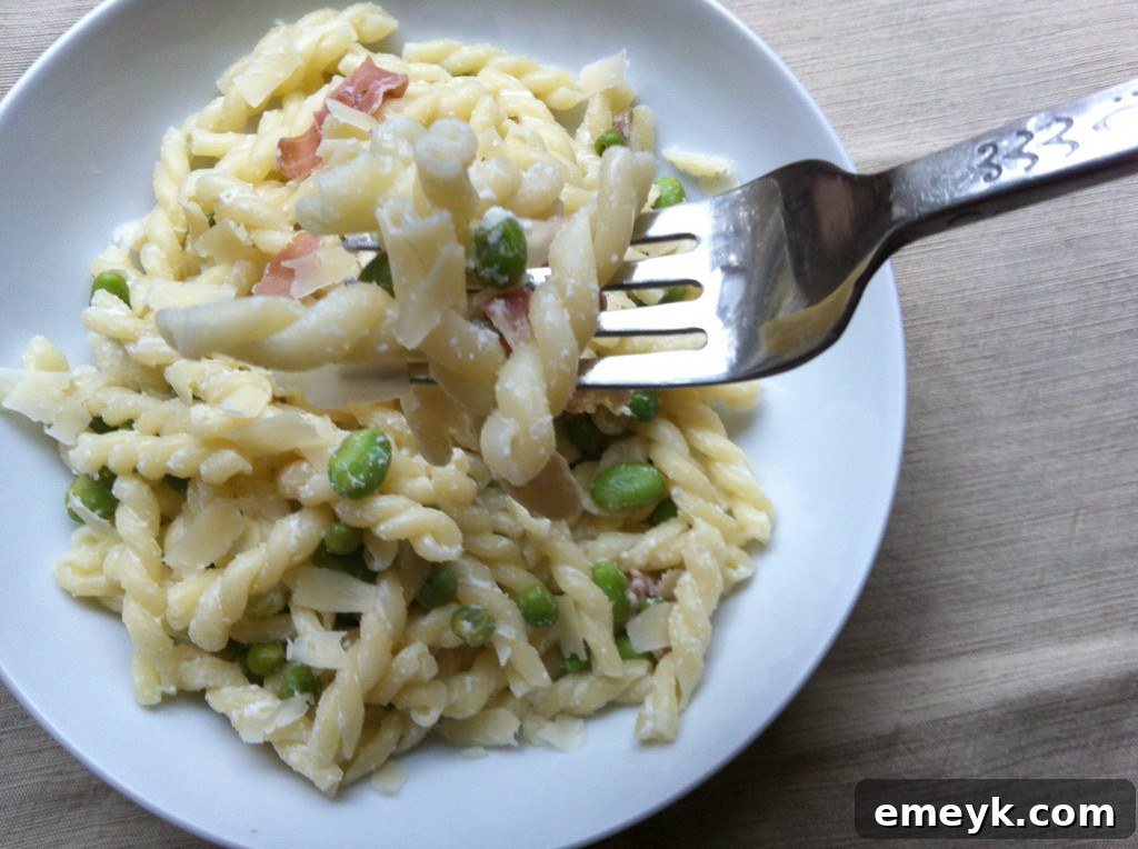 Cooked pasta with peas, favas, and prosciutto in a bowl.