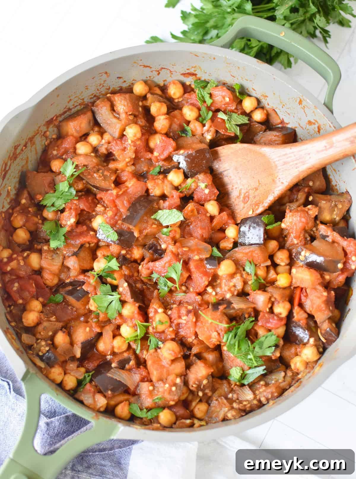 Lebanese Maghmour Hearty Eggplant and Lentil Casserole 6 Lebanese Moussaka simmering in a large skillet, with a wooden spoon resting in the rich mixture of eggplant, chickpeas, and tomatoes.