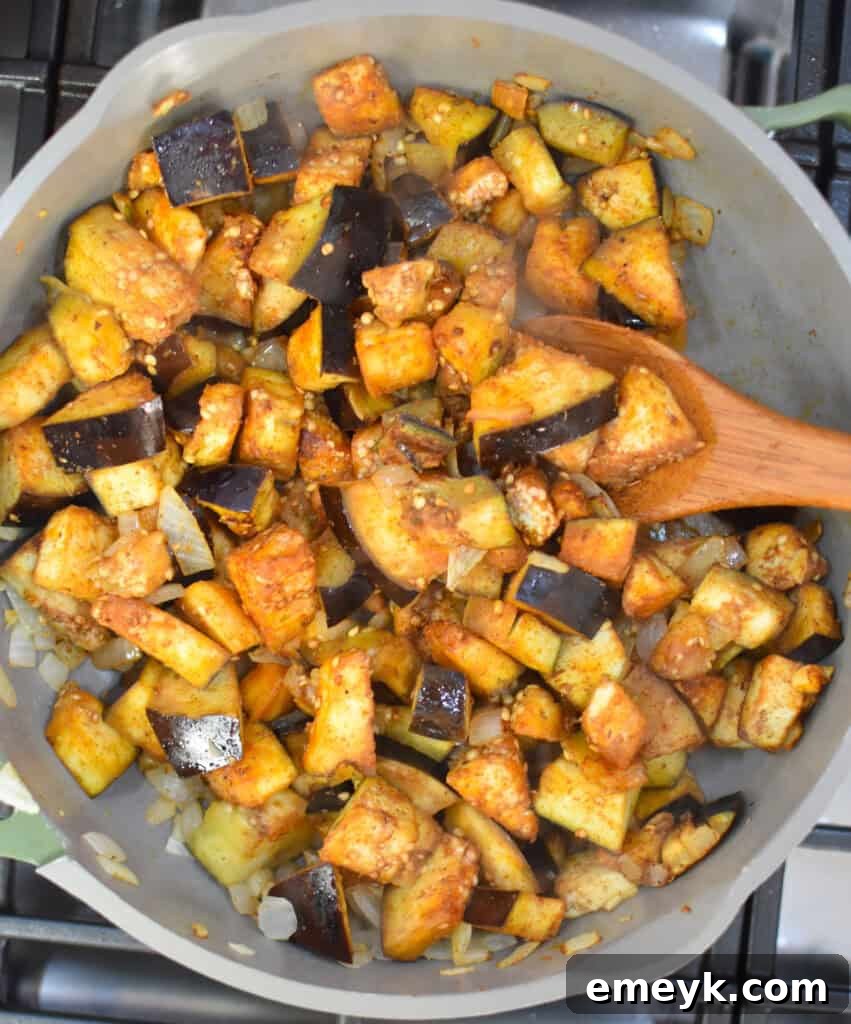 Lebanese Maghmour Hearty Eggplant and Lentil Casserole 8 Close-up of eggplant and chickpeas cooking together in a large skillet, absorbing the spices.