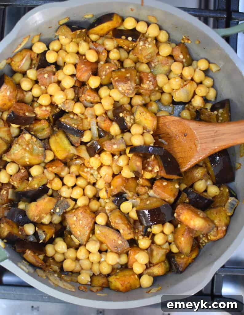 Lebanese Maghmour Hearty Eggplant and Lentil Casserole 9 The skillet now containing eggplant, chickpeas, and diced tomatoes, simmering to combine all the delicious elements.