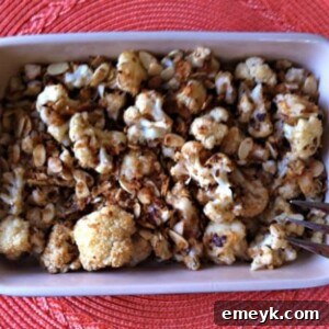 A collection of fresh ingredients for the roasted cauliflower recipe, including a head of cauliflower, almonds, panko breadcrumbs, and garlic.
