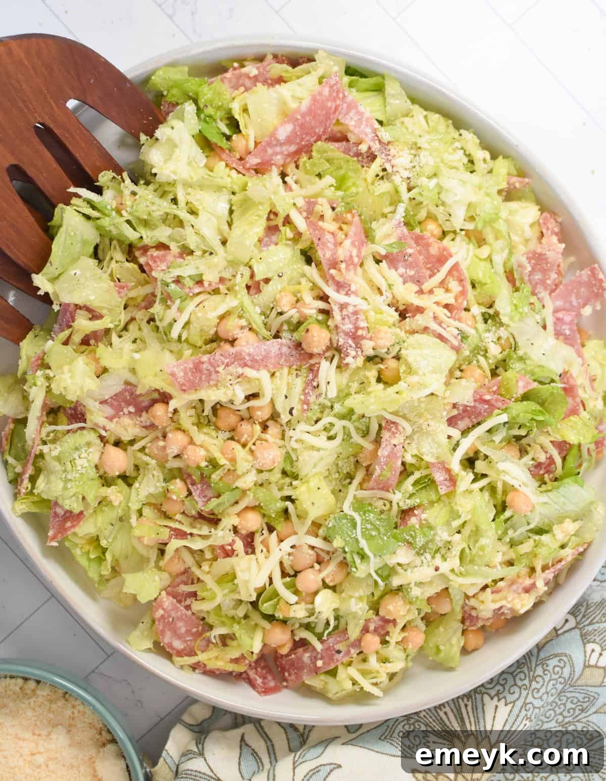 Copycat La Scala Chopped Salad served in a elegant white bowl with wooden serving utensils, ready to be enjoyed.