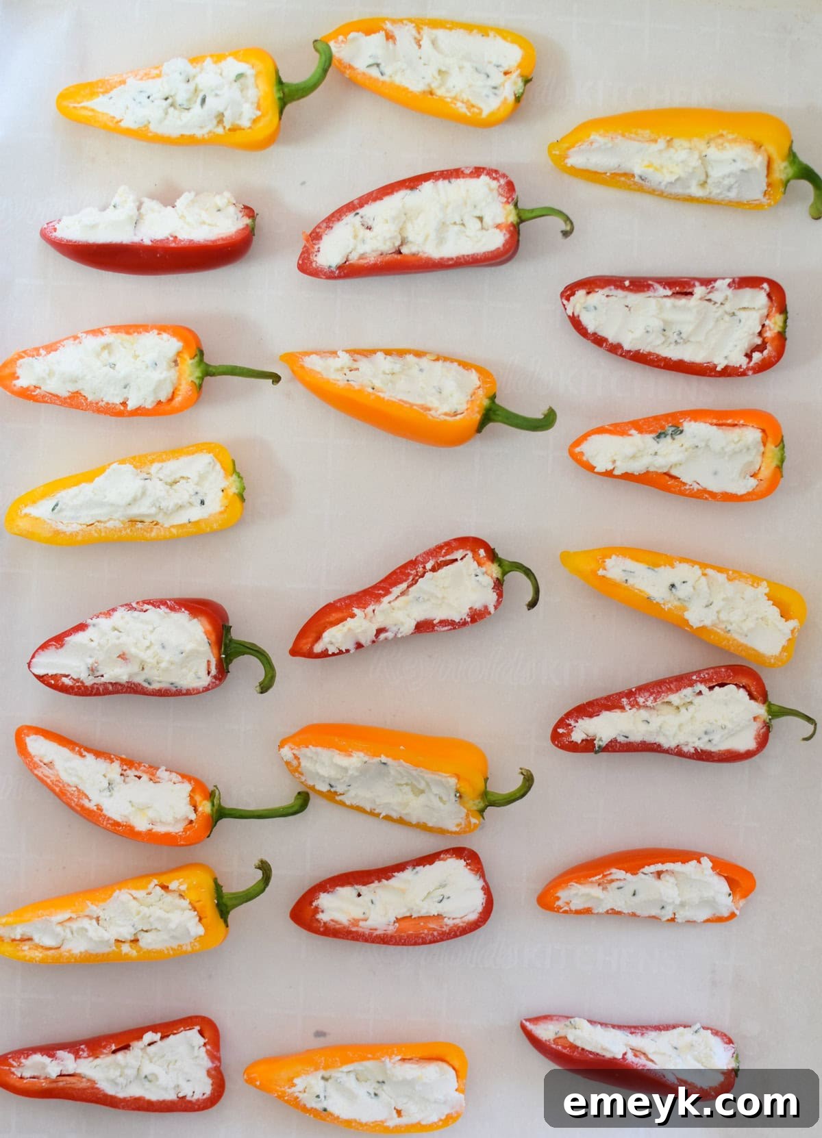Creamy Goat Cheese-Filled Mini Peppers 11 Goat Cheese Stuffed Mini Peppers neatly arranged on a parchment-lined baking sheet, ready for the oven.