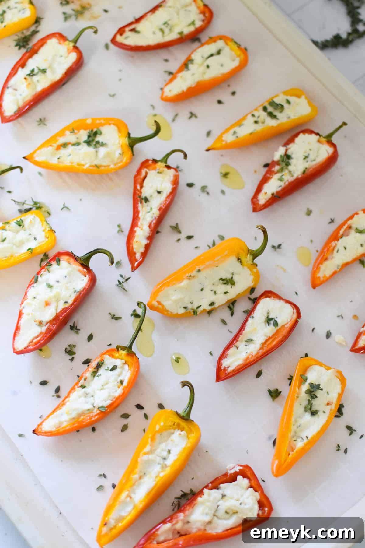 Creamy Goat Cheese-Filled Mini Peppers 12 Freshly baked Goat Cheese Stuffed Mini Peppers on a baking sheet, showing melted cheese and softened peppers.