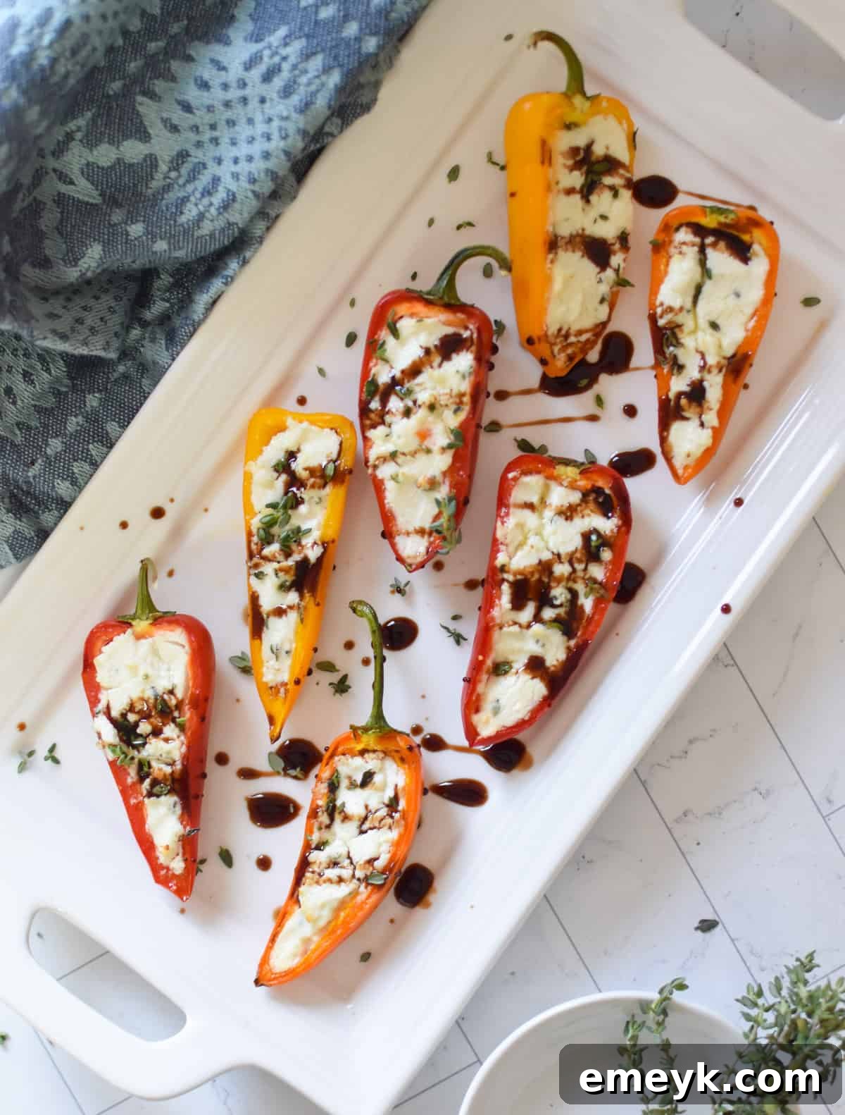 Creamy Goat Cheese-Filled Mini Peppers 7 Mini sweet peppers halves filled with a creamy goat cheese and herb mixture, arranged on a cutting board before baking.