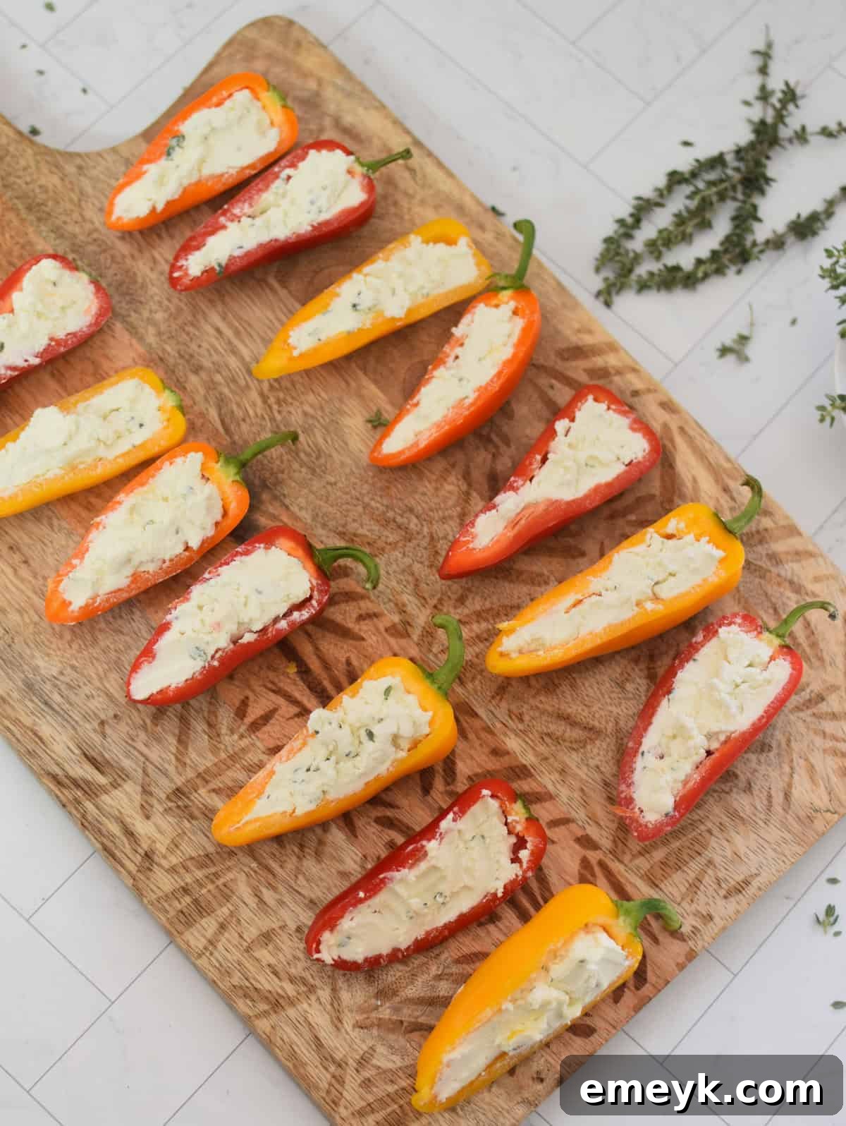 Creamy Goat Cheese-Filled Mini Peppers 10 Mini sweet peppers expertly stuffed with goat cheese filling, arranged on a cutting board.