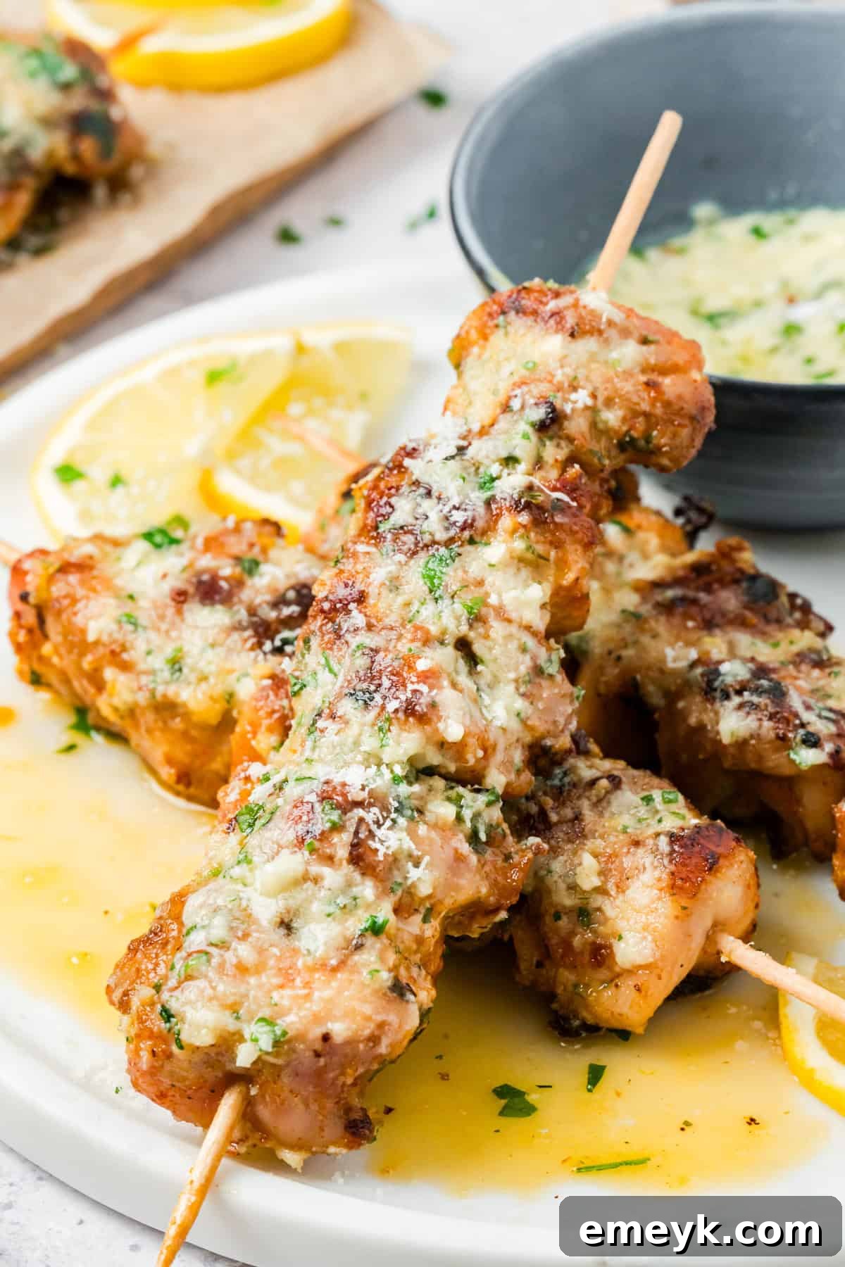Juicy chicken thighs skewers brushed with garlic parmesan butter sauce, garnished with fresh parsley.