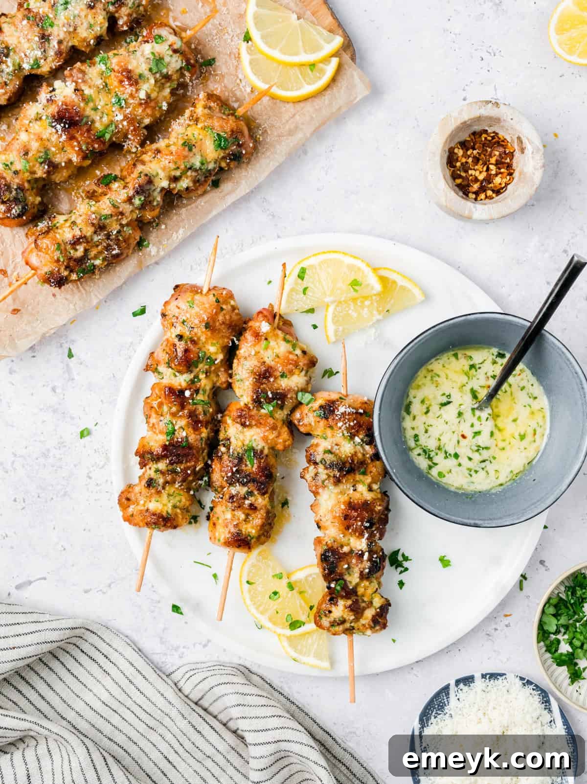 Garlic Parmesan Grilled Chicken Skewers garnished with fresh lemon wedges and parsley.