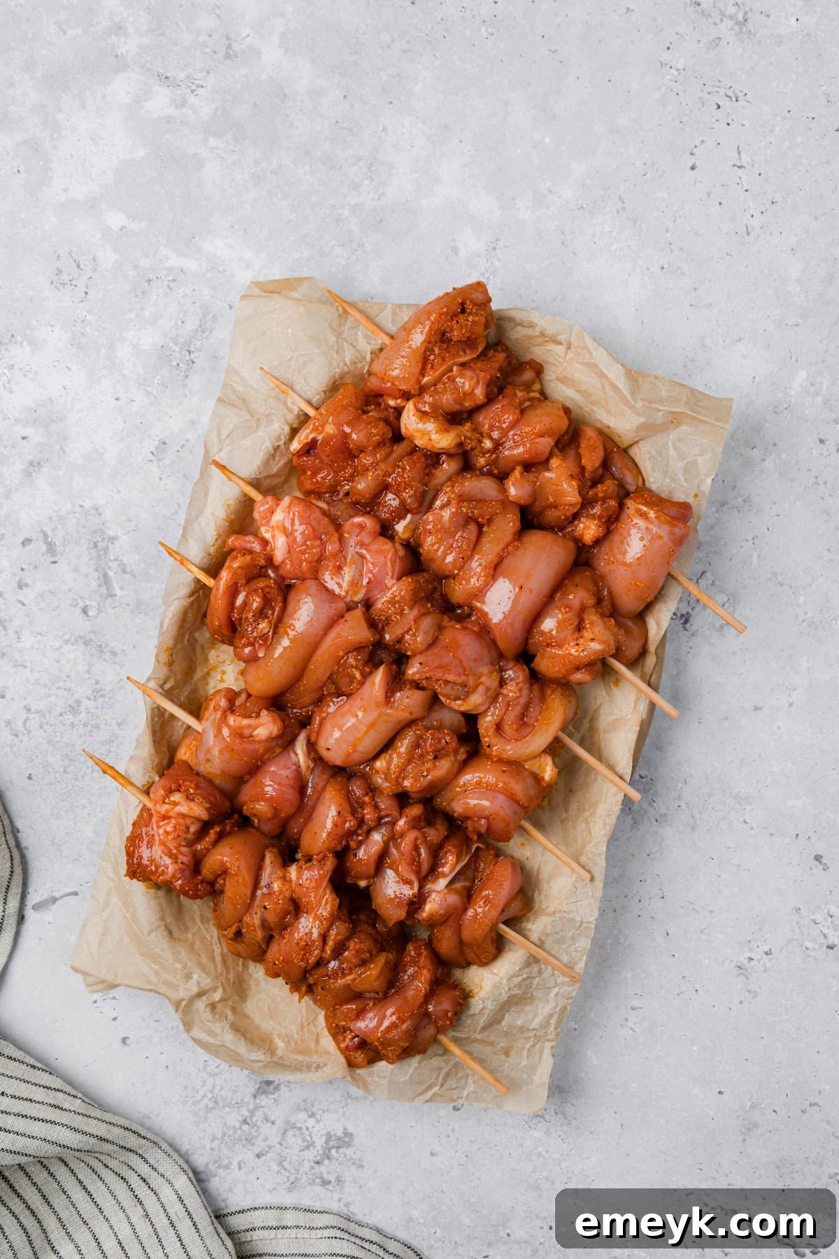 Marinated chicken threaded tightly onto wooden skewers.