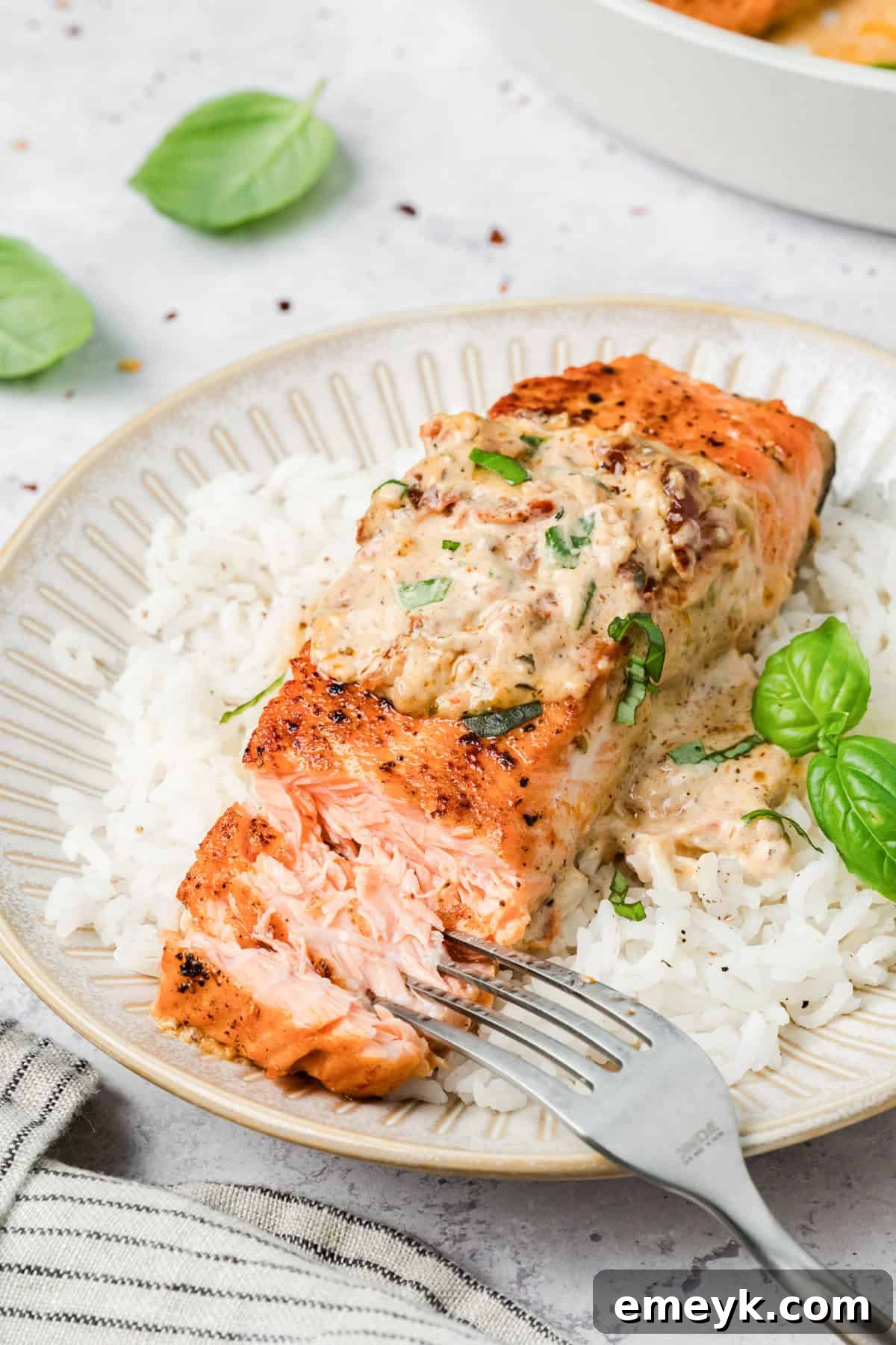 Marry Me Salmon on a plate with a fork flaking the salmon 