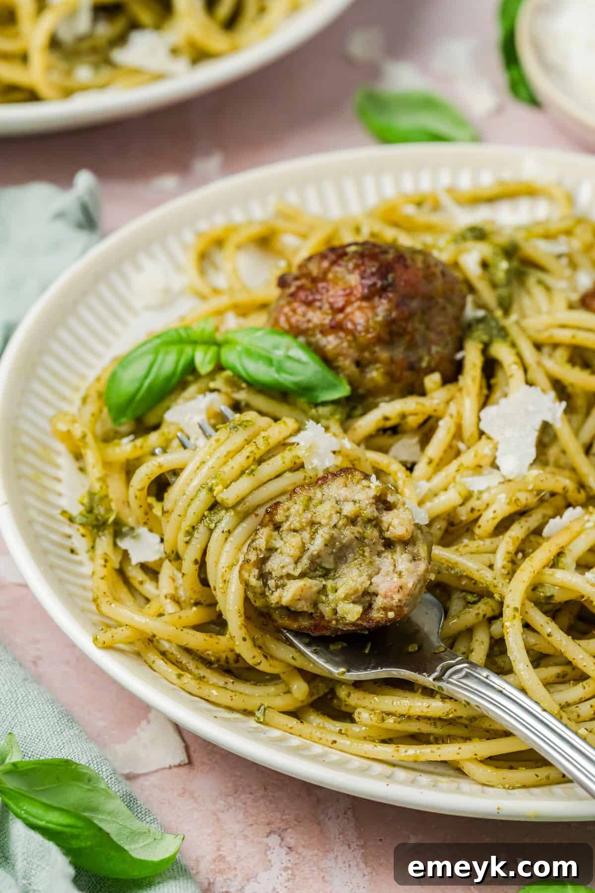 Meatballs in pesto sauce on a plate with a fork.