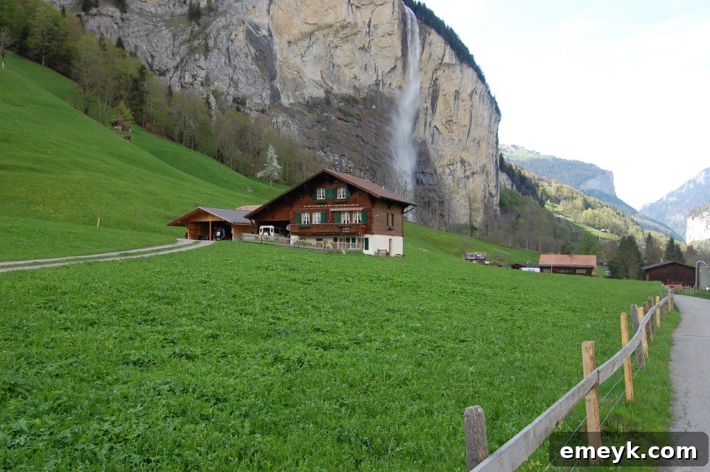 A picturesque Swiss Chalet nestled in a vibrant green landscape with Alpine mountains