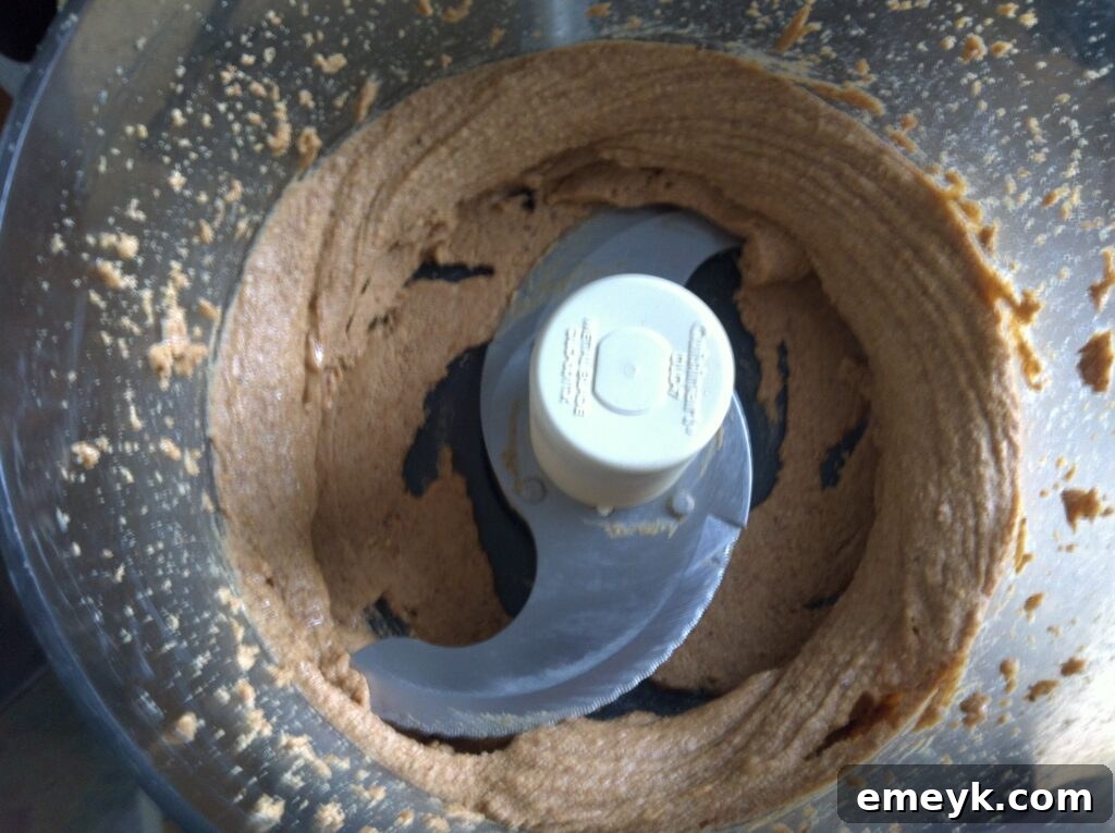 Smooth almond butter forming in the food processor, reaching its creamy consistency
