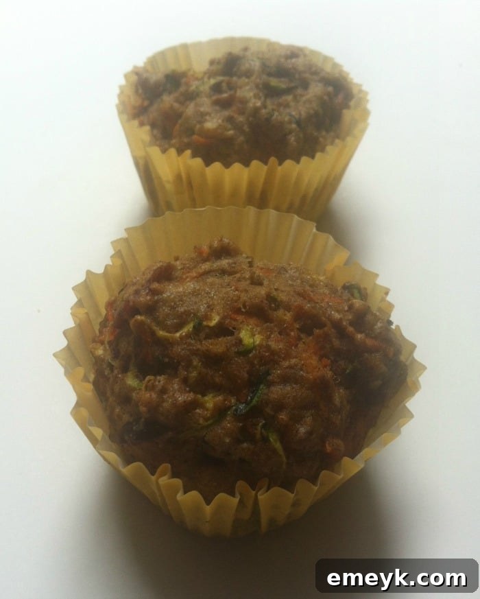 Close-up of a freshly baked Carrot Zucchini Muffin, showing flecks of vegetables and a golden-brown top