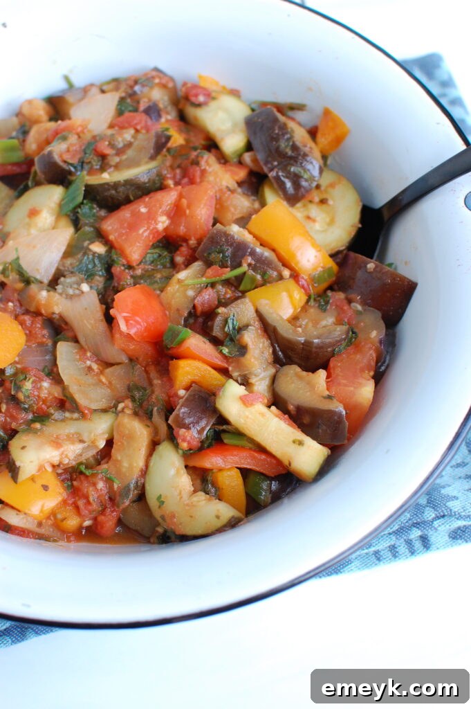 Close-up of Ratatouille in a white bowl, with a spoon revealing the rich texture.
