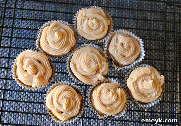 Close-up of frosted pumpkin cupcakes, highlighting the generous maple cinnamon cream cheese frosting
