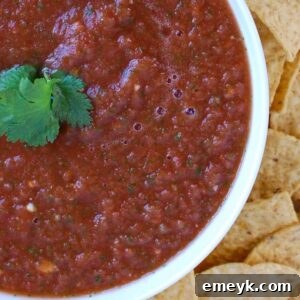 Overhead view of homemade salsa in a bowl with a side of crispy tortilla chips, ready to be served