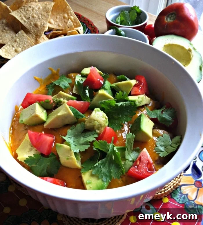Creamy Baked Avocado Black Bean Dip with vibrant garnishes and tortilla chips