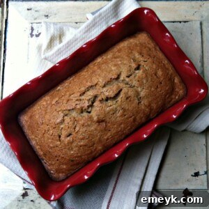 A golden brown loaf of Zucchini Applesauce Bread cooling on a wire rack.