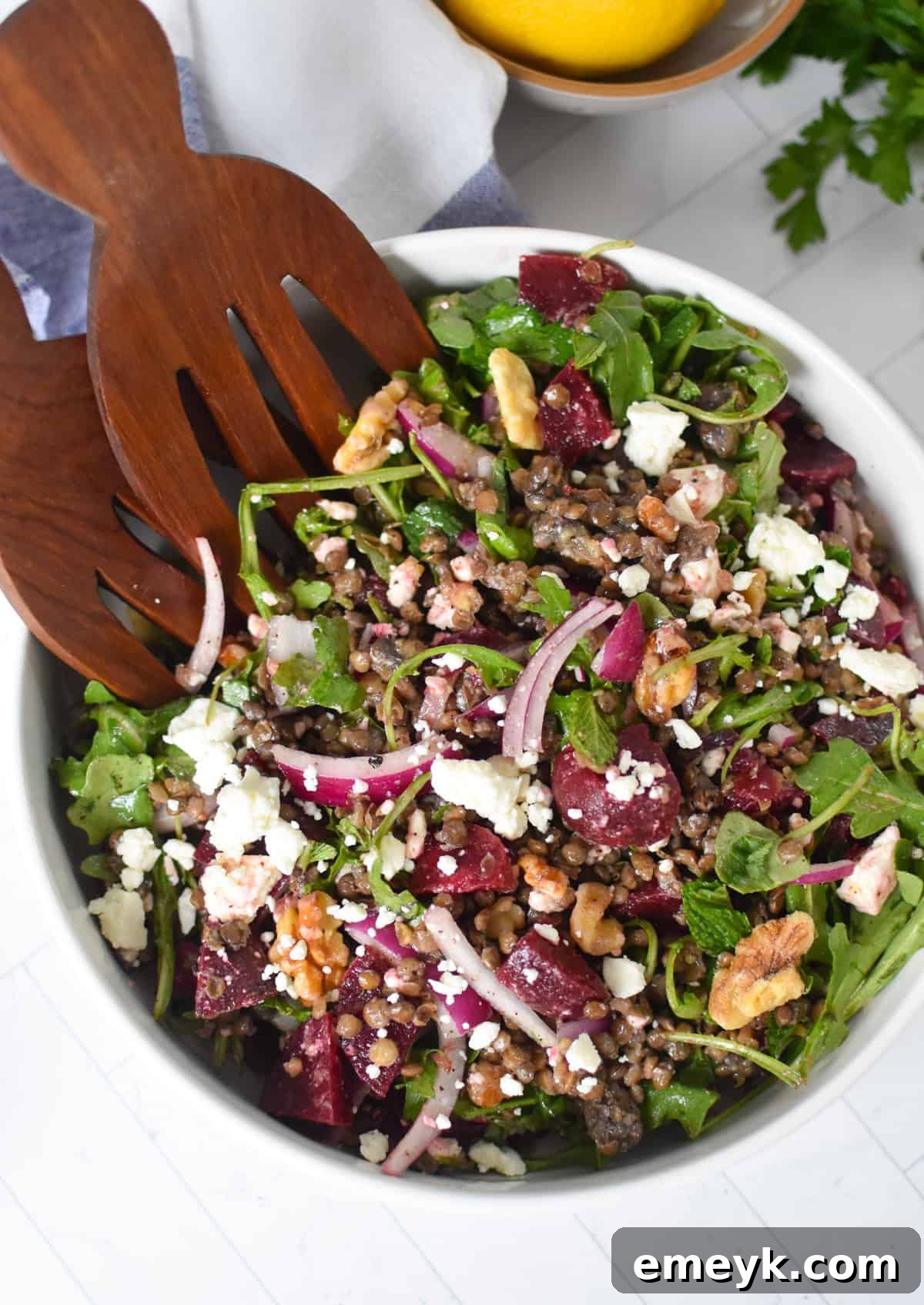 Delicious Lentil and Beet Salad served in a bowl with two wooden spoons, highlighting its vibrant colors and fresh ingredients.