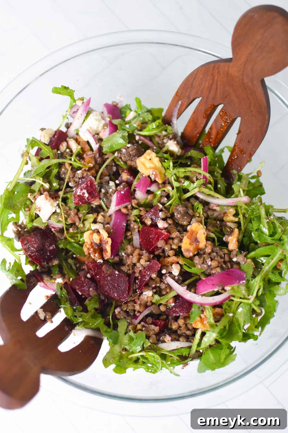 The Mediterranean Lentil Beet Salad with Feta and Walnuts beautifully presented in a clean white bowl with wooden serving spoons.