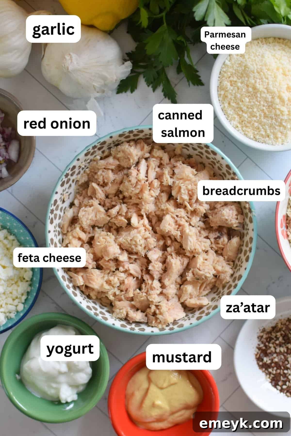 A selection of fresh ingredients for Mediterranean Salmon Cakes, including canned salmon, feta, and herbs
