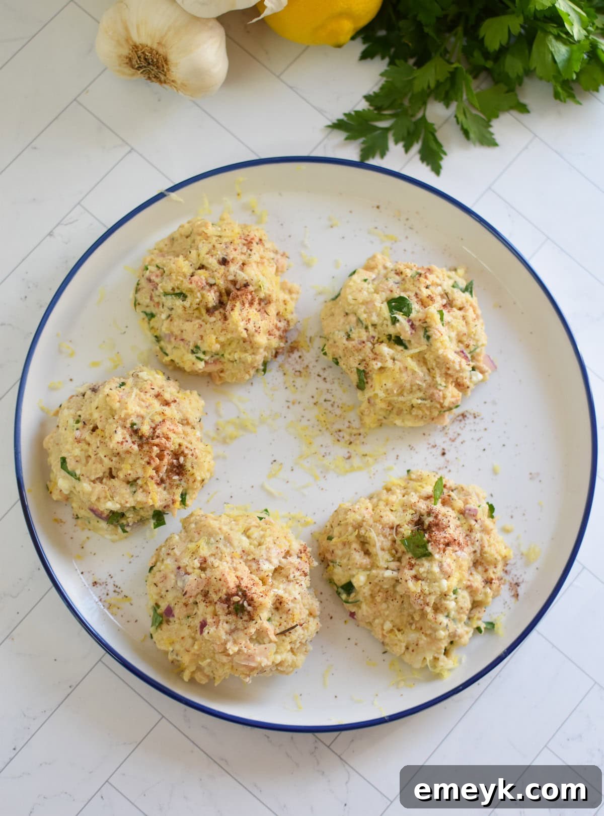 Mediterranean Salmon Patties formed on a plate, lightly coated with breadcrumbs