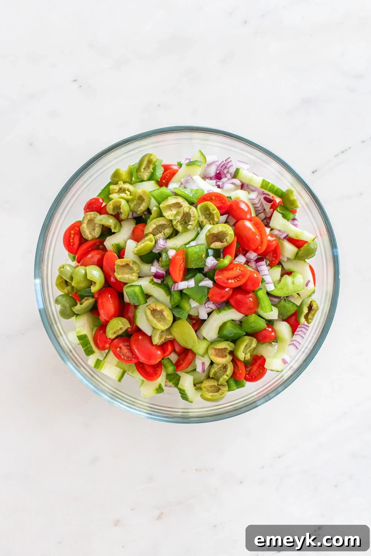 Chopped vegetables being added to the bowl with butter beans and dressing.