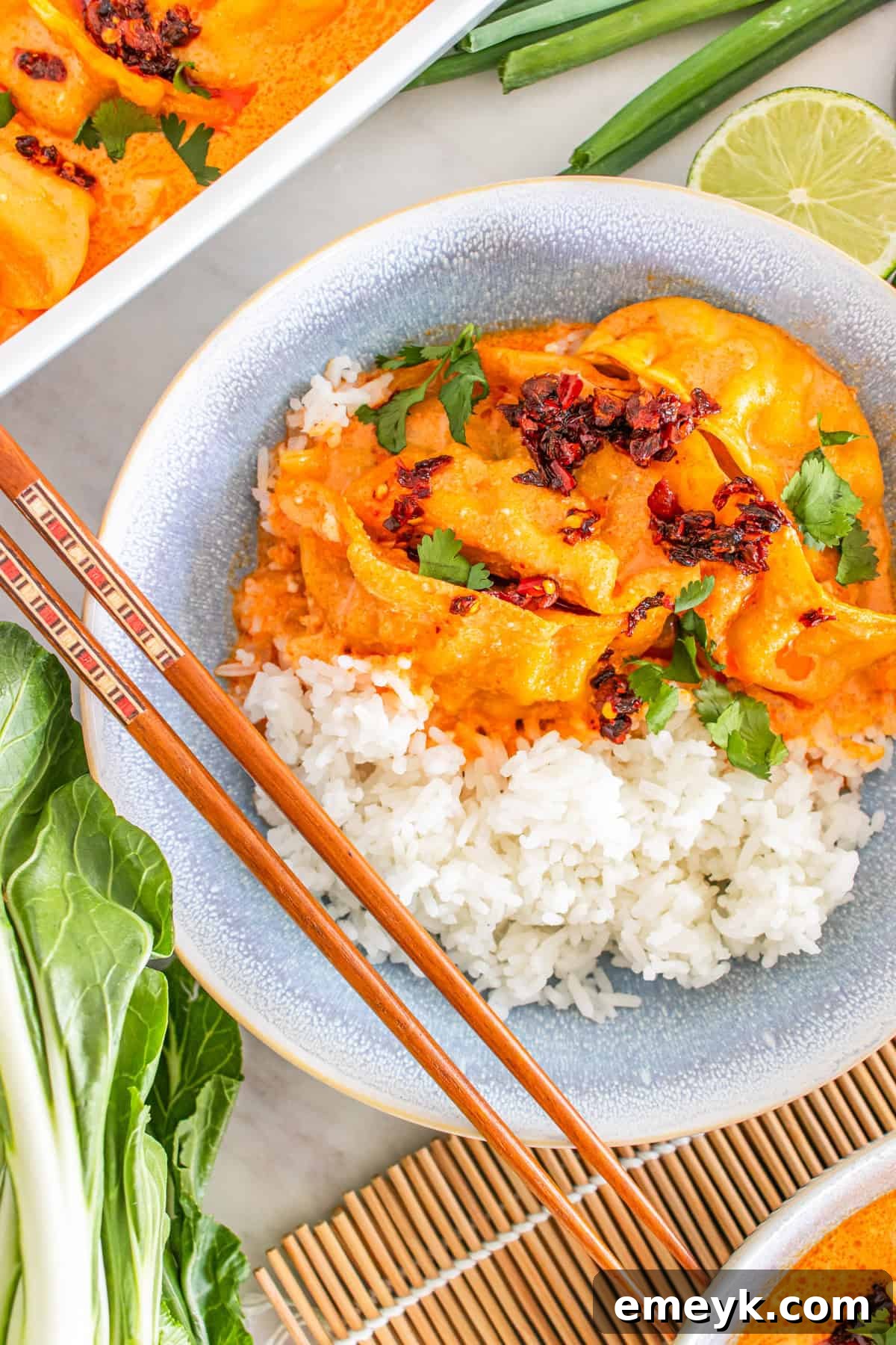 TikTok viral baked dumplings with creamy coconut curry sauce, garnished with chili crisp, green onions, and fresh cilantro, served in a single pan.
