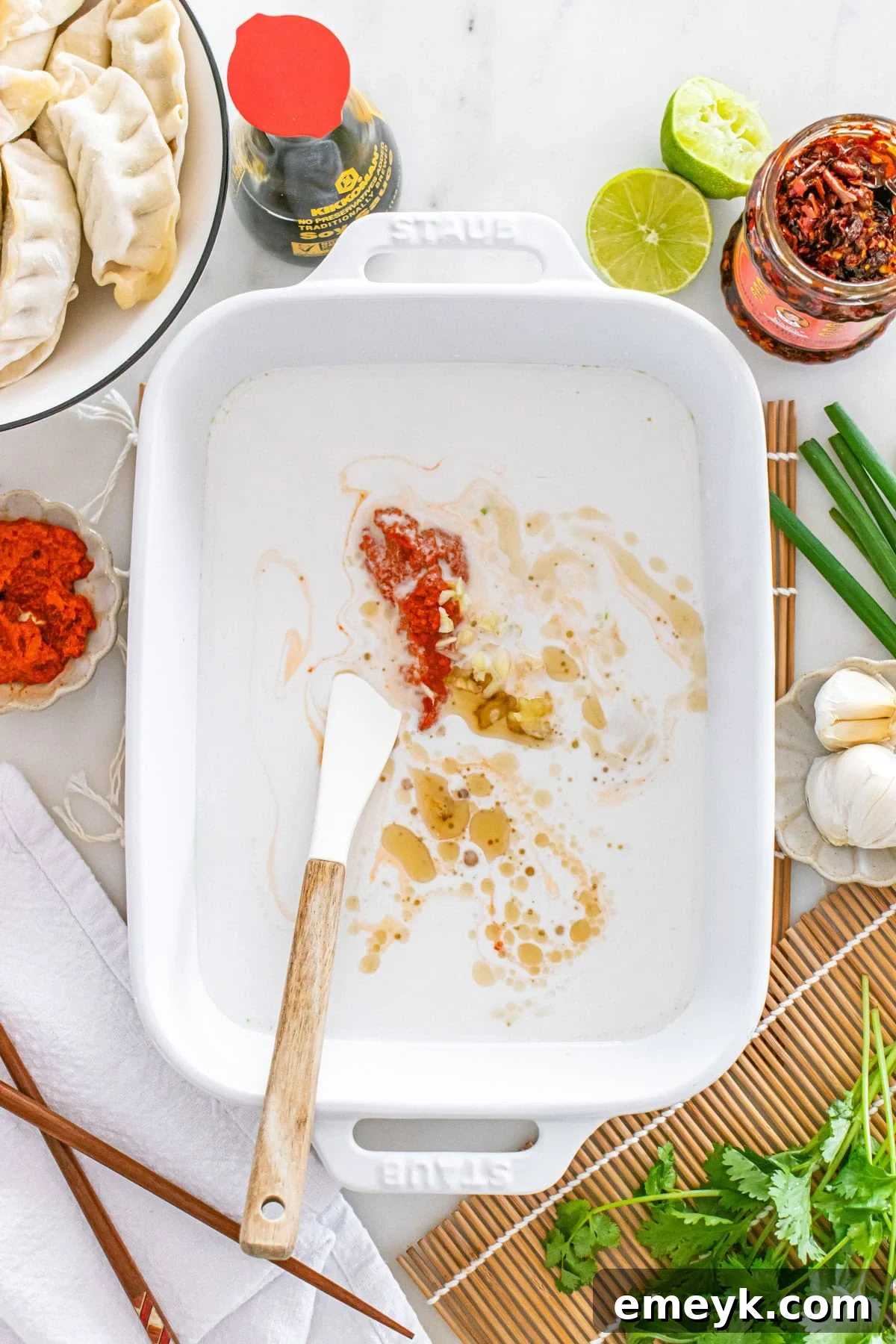 The creamy coconut curry sauce being mixed in a baking pan, ready for dumplings.