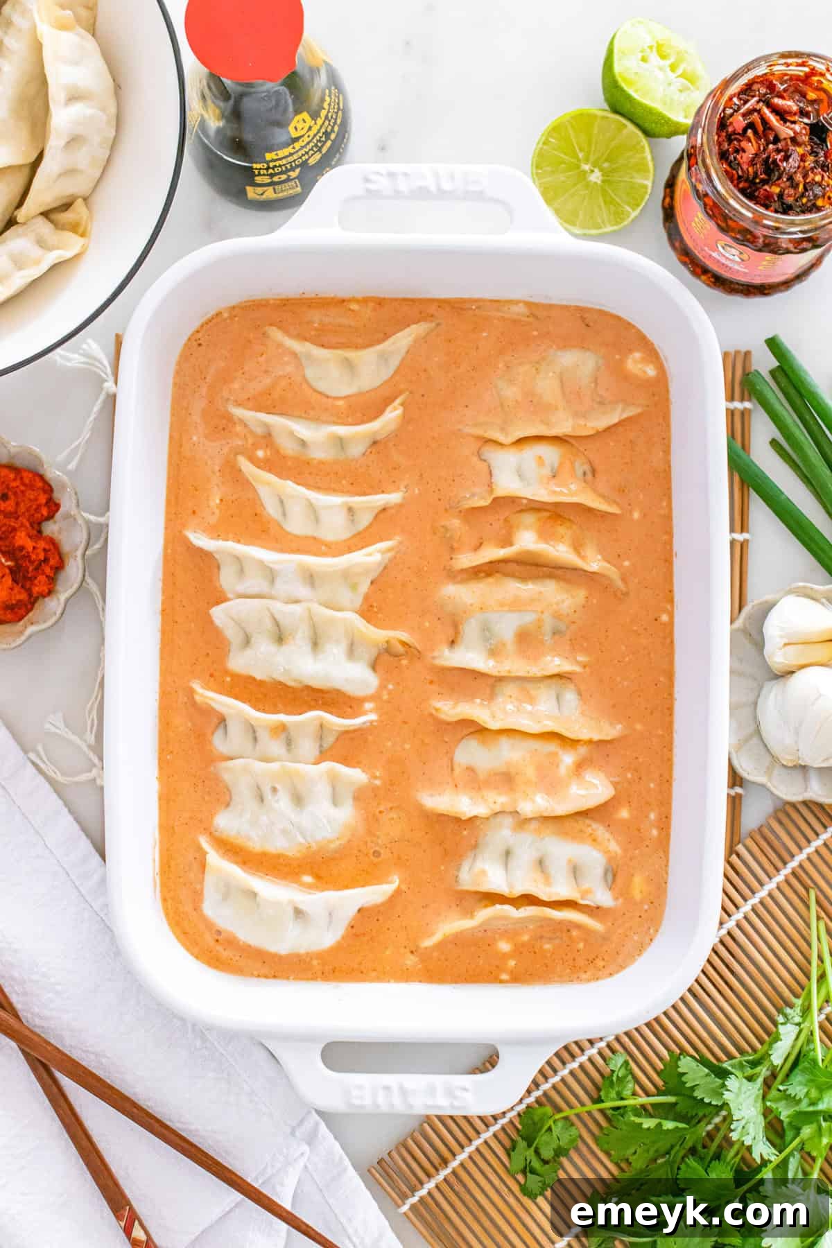 Frozen dumplings nestled into the coconut curry sauce in a baking pan.