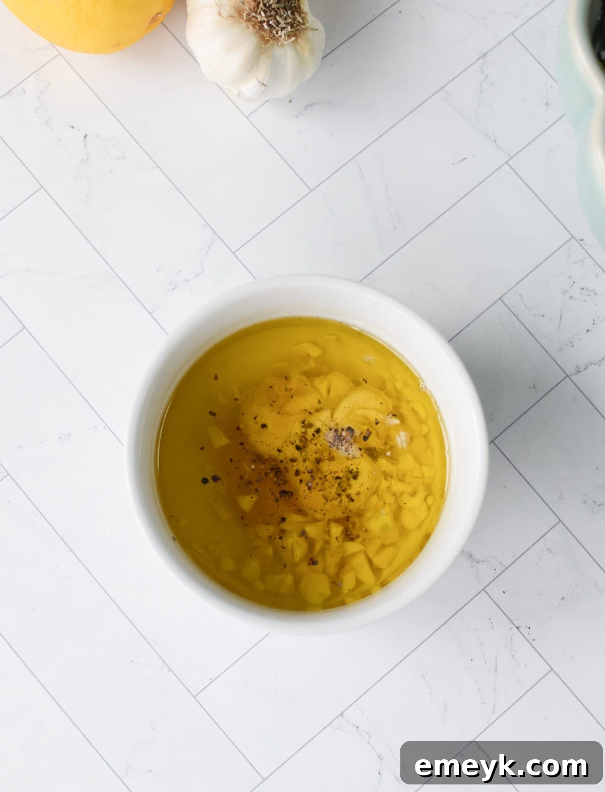 Ingredients for the tangy salad dressing in a small glass jar, including olive oil, lemon, and spices.