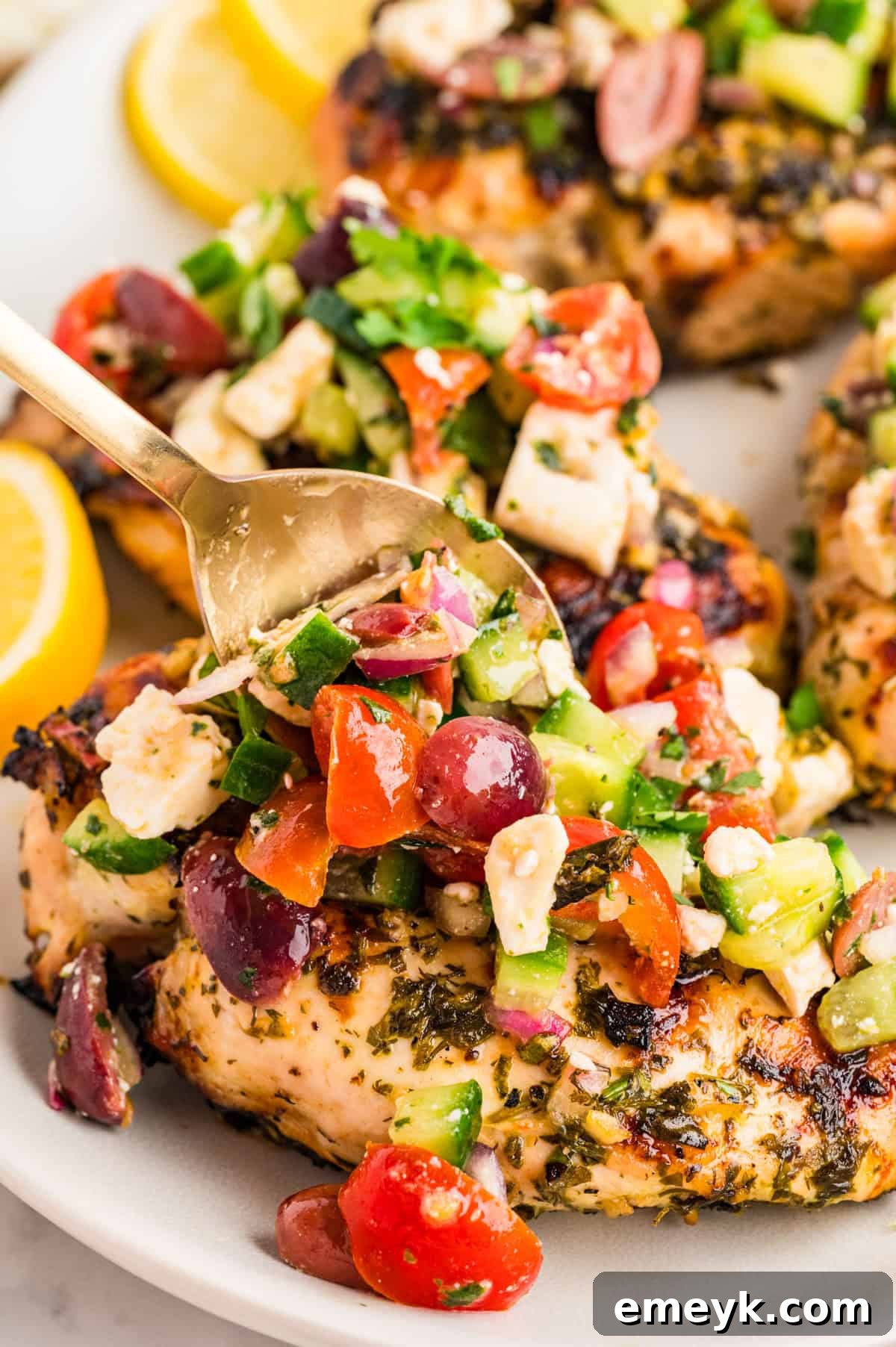 Close up of Mediterranean chicken topping with cucumber cherry tomatoes kalamata olives and feta crumbles