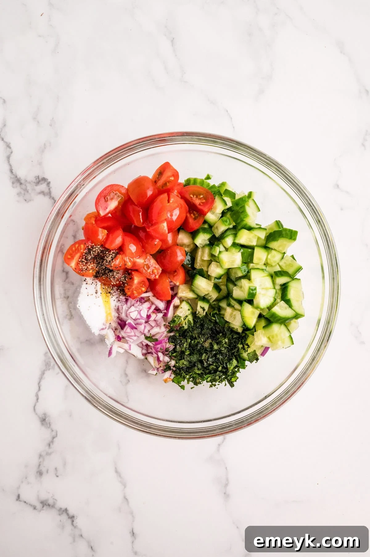 Mediterranean chicken topping with cucumber tomatoes olives and fresh basil in a mixing bowl
