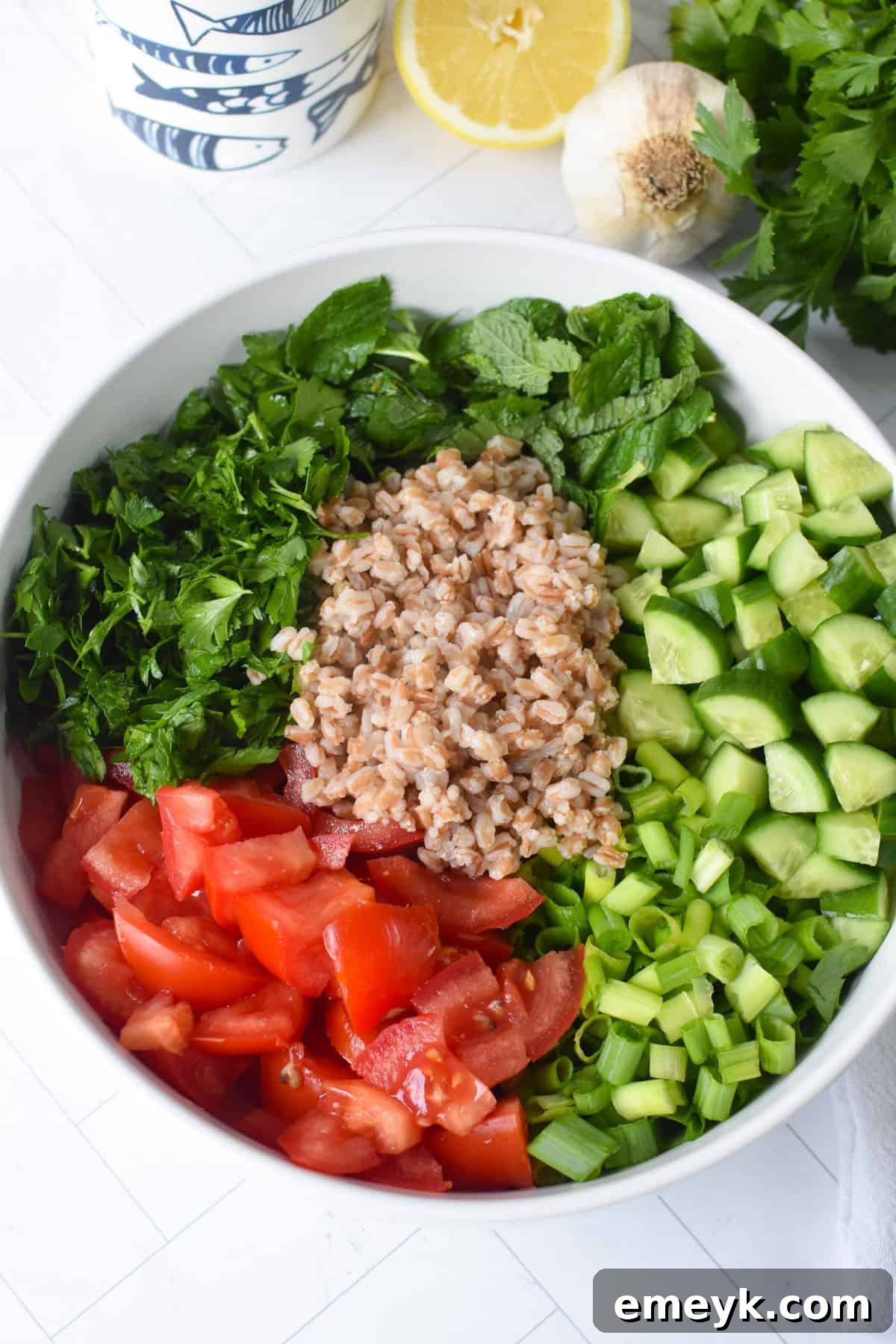Mediterranean Farro Tabbouleh 7 Simple and vibrant Farro Tabbouleh Salad in a clear glass bowl, showcasing its fresh ingredients.